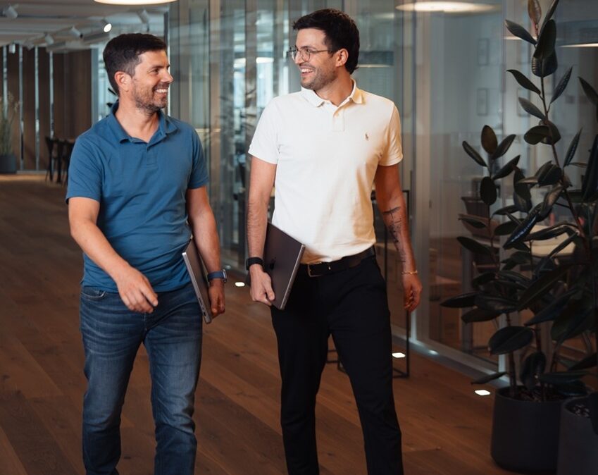 Zwei Männer spazieren durch ein Bürogebäude.