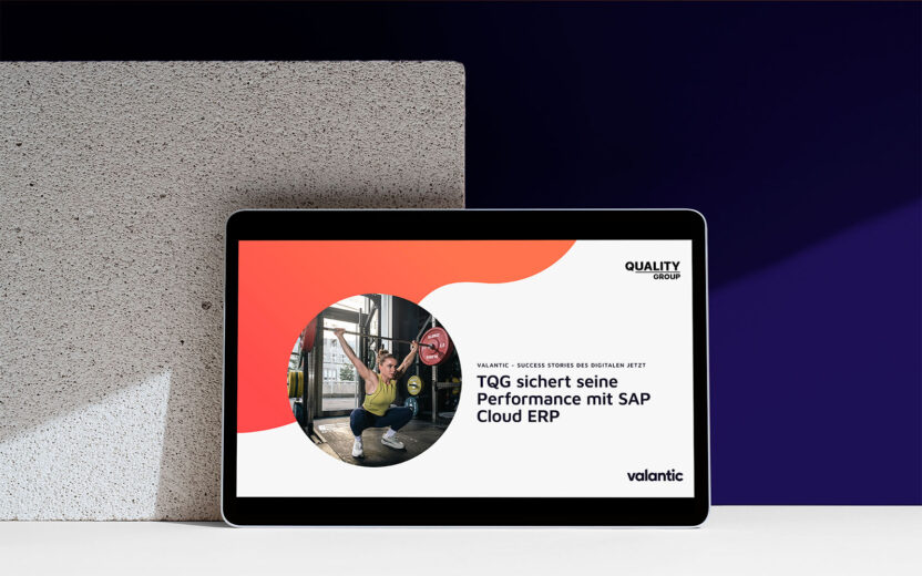 Titelseite der Success Story zur Einführung von SAP Cloud ERP bei The Quality Group auf einem Tablet vor einem Hintergrund, der Teilweise aus Stein und teilweise farbig schwarz-lila ist.