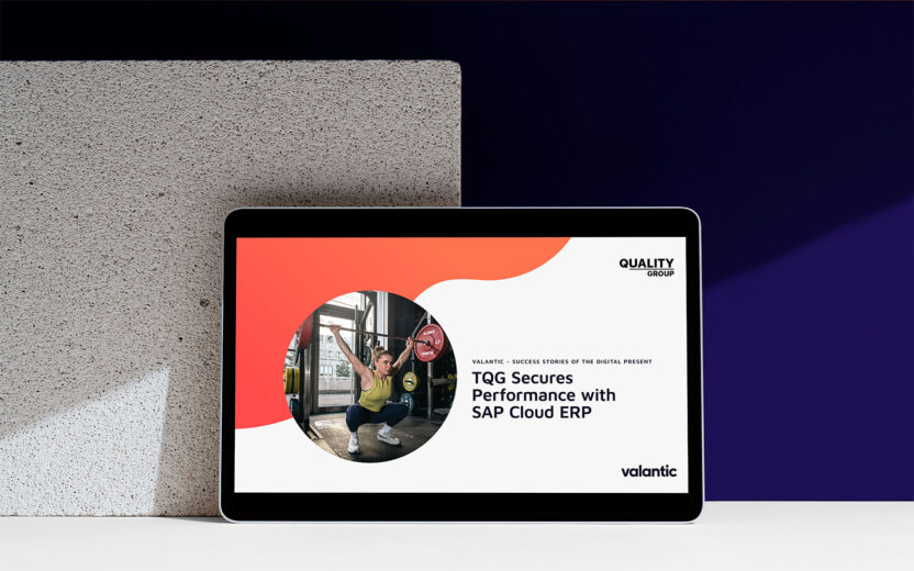Cover page of the success story about the implementation of SAP Cloud ERP at The Quality Group on a tablet against a background that is partly stone and partly black and purple.
