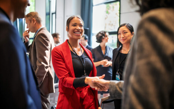Confident businesswomen handshaking while standing in corridor of an auditorium. Female professionals greeting each other convention center.