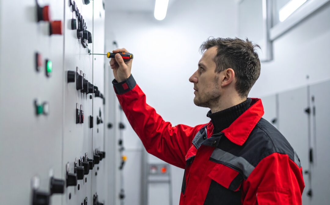 technician working on a industrial panel. side view shot of him using a screwdriver