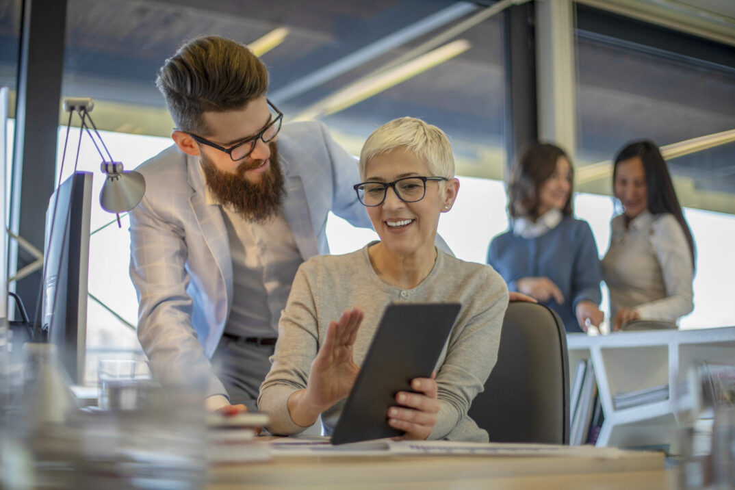 Hermosa mujer de negocios madura está hablando con un colega joven barba