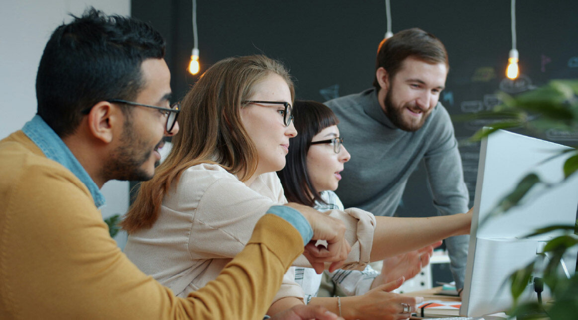 Vier Personen arbeiten gemeinsam am Computer und testen das valantic KI Tool für die Migration von Daten in ihrem SAP S/4HANA Projekt