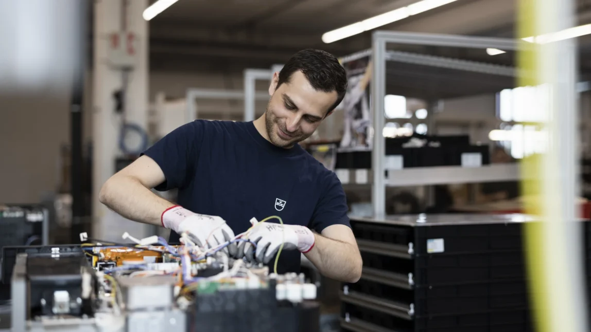 Bild eins V-Zug Mitarbeiters mit weissen Handschuhen der sich handwerklich betätigt, digitale Markenpositionierung