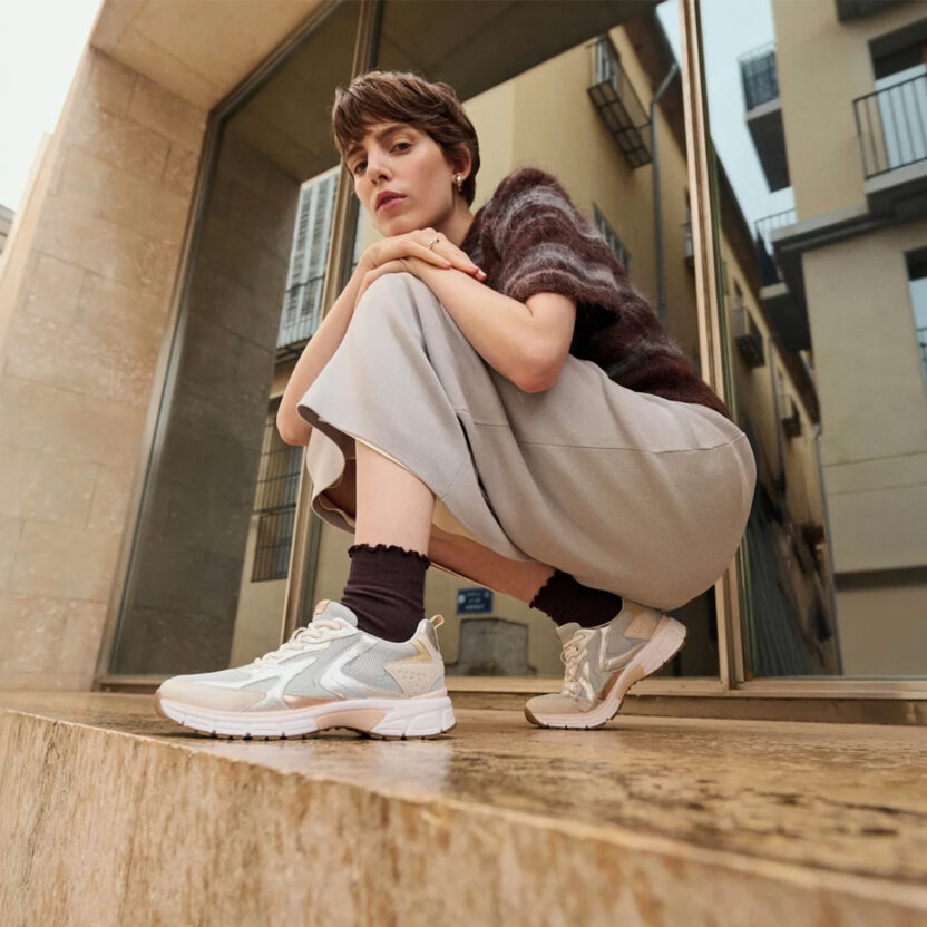 Frau sitzt vor einem Gebäude und trägt moderne Gabor Sneaker in urbaner Umgebung