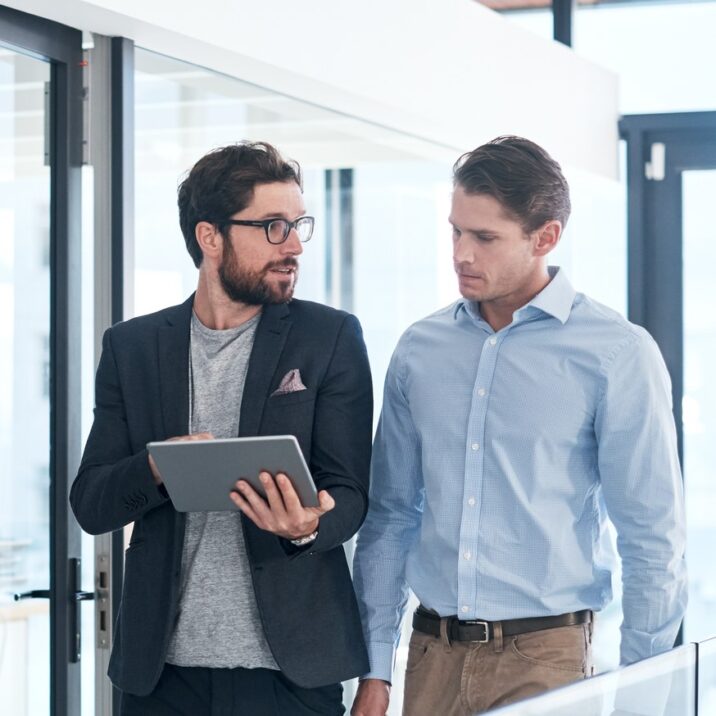 Dos hombres de negocios conversan mirando una tableta