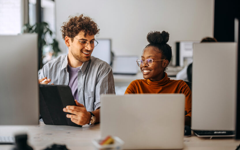 Zwei junge Kollegen arbeiten zusammen in einem modernen Büro,