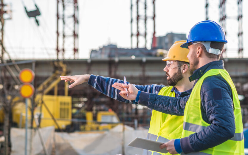 Two people at a construction site wearing safety gear