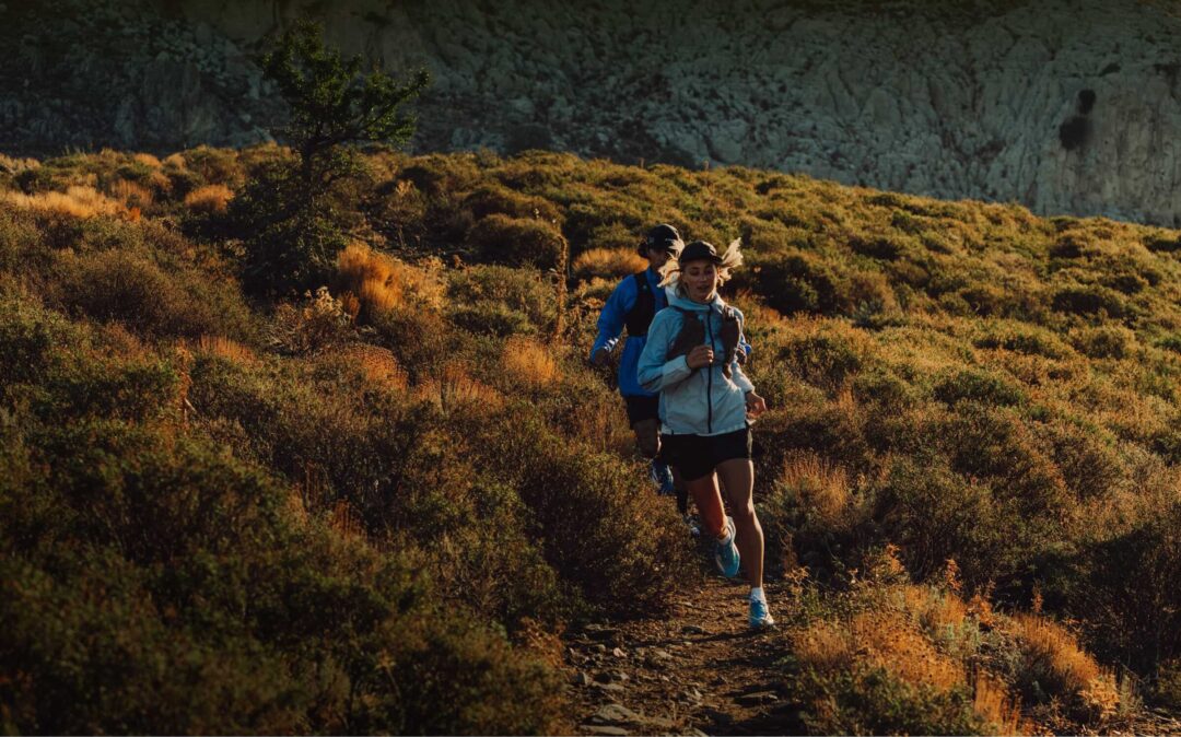 Two runners trail running on a mountain trail in the golden evening light