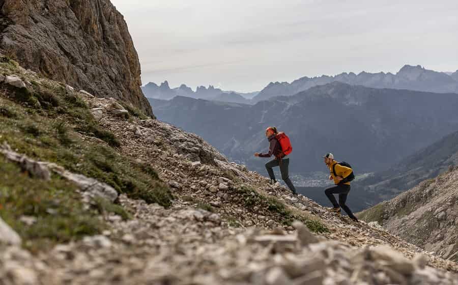 Two hikers on a challenging mountain trail with a stunning Alpine backdrop