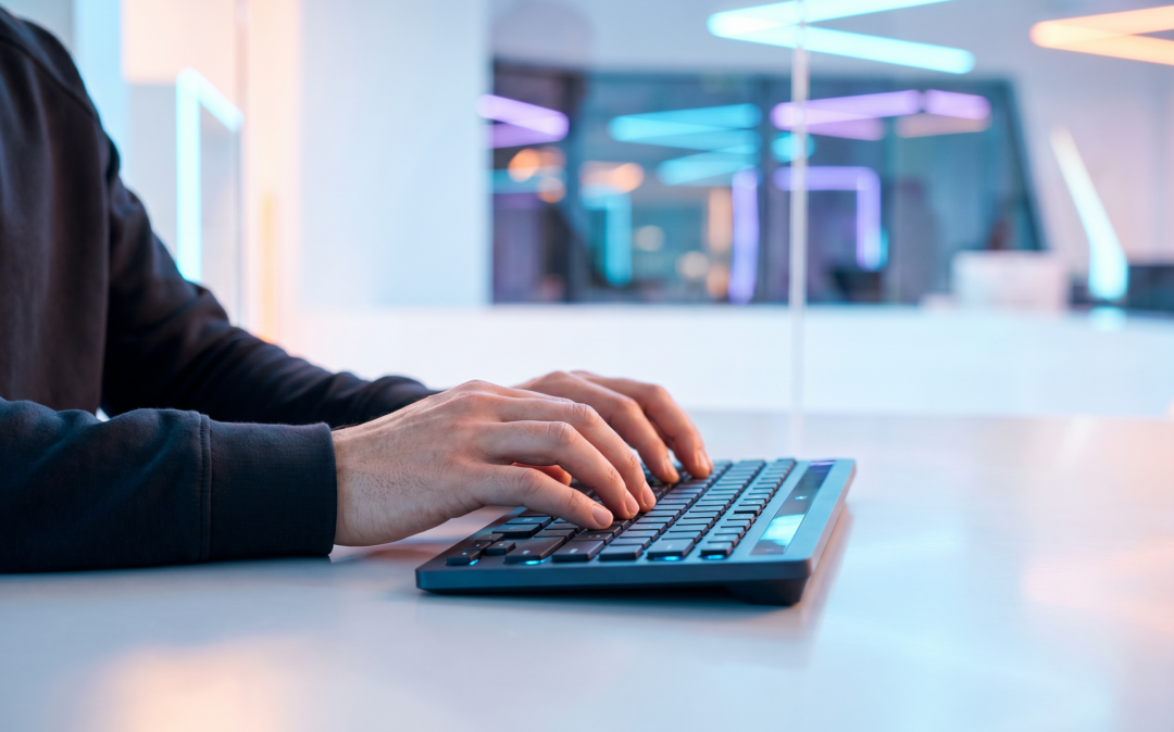 Close-up of hands typing on an illuminated keyboard