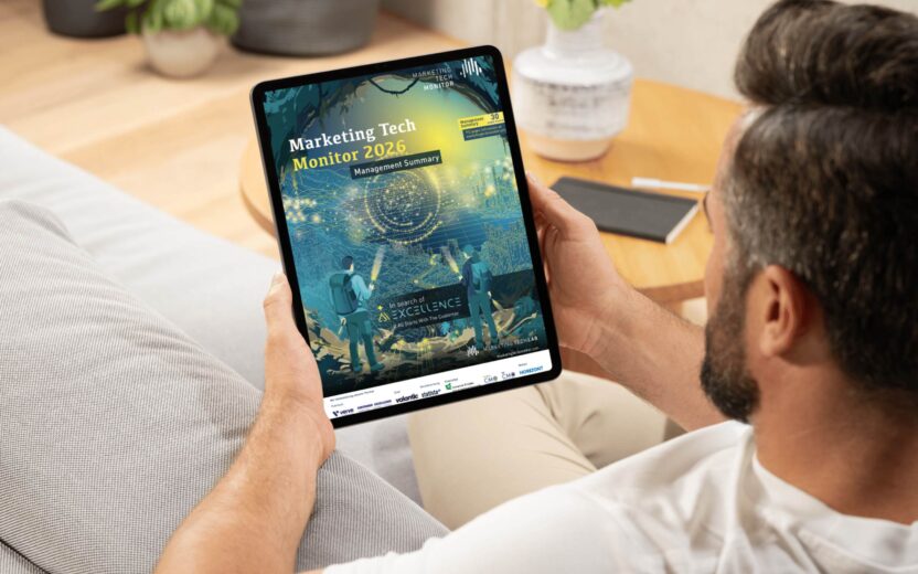 Mann auf einem Sofa liest die Management Summary zum Marketing Tech Monitor 2026 auf einem Tablet.