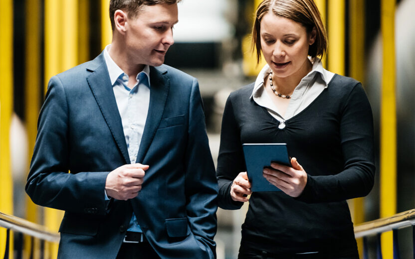 Two business people walking down a dark factory corridor