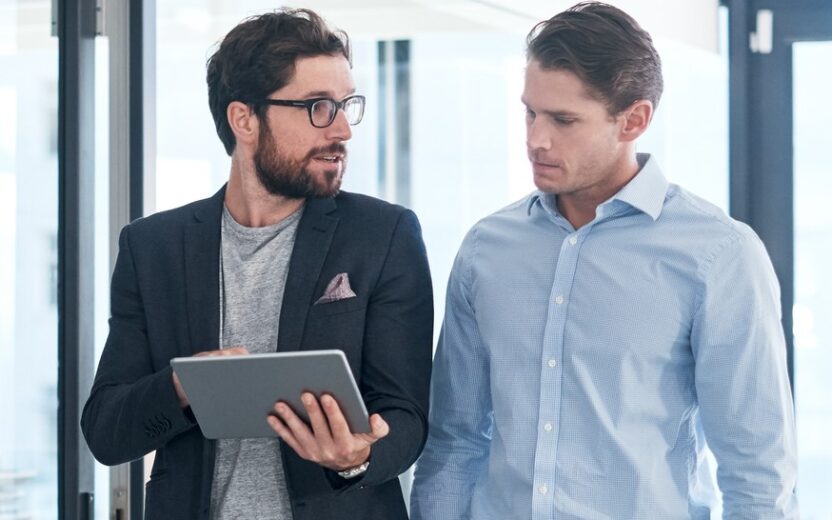 Twee zakenlieden die met elkaar in gesprek zijn terwijl ze naar een tablet kijken