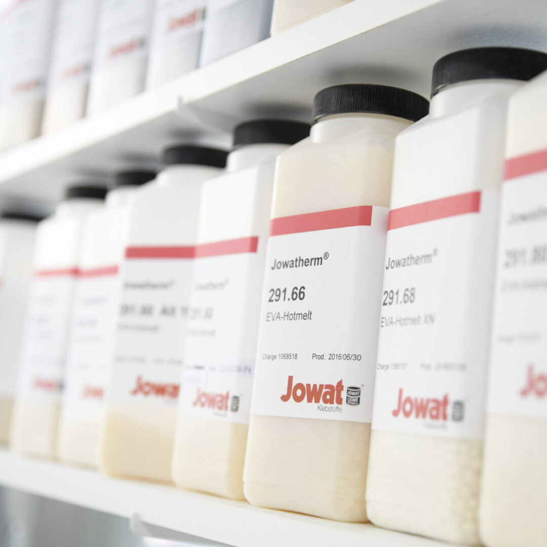 Nahaufnahme von einer Reihe Plastikflaschen mit Klebstoffen der Jowat SE