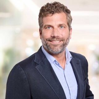 Photo by Martin Vierrath, portrait of a smiling man wearing a blazer and shirt