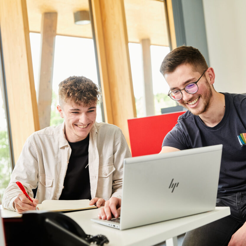 Zwei junge Mitarbeitende der Jowat SE arbeiten vor einem aufgeklappten Laptop