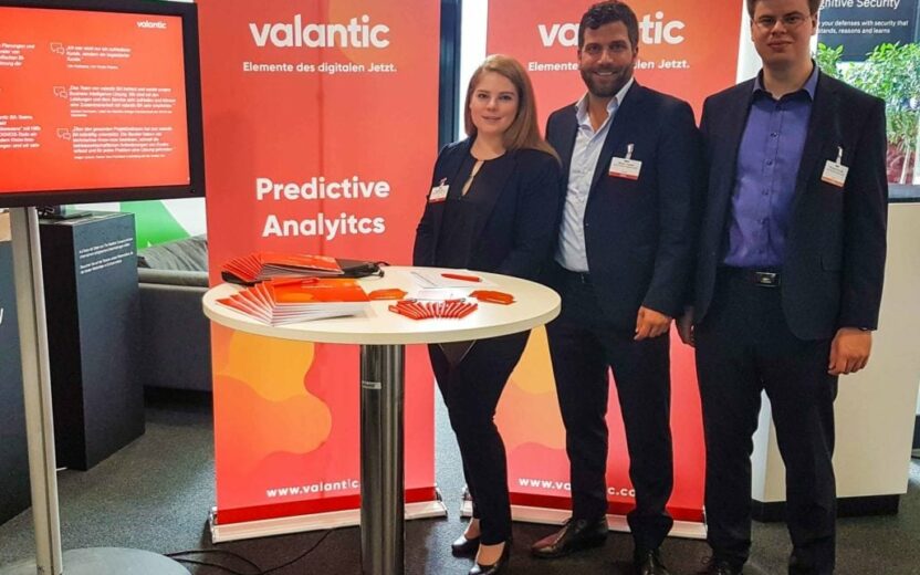 Bild von drei Personen an einem Messestand, Das valantic Team präsentiert als Aussteller und Sponsor auf dem TM1 / Planning Analytics Anwendertag in Stuttgart seine Cognitive Analytics und Predictive Analytics Lösungen.