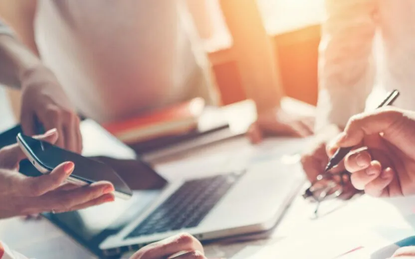 Bild einer Meetingrunde mit Handy, Stift und Laptop im Hintergrund: SAP S4/HANA Deep Dive Workshop