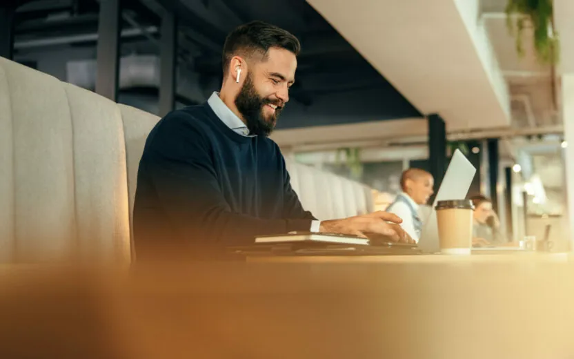 Cheerful young businessman working on his laptop in a co-working space.