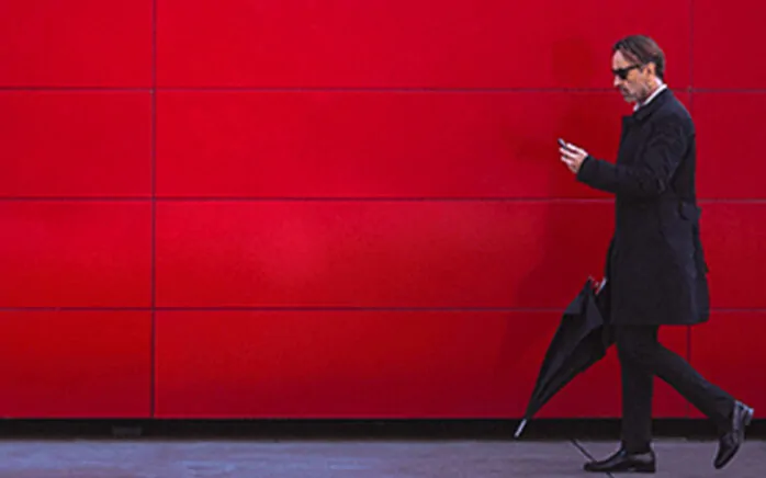 Picture of a man with black coat and black umbrella in front of red wall, valantic Case Study E-Plus Telefonica
