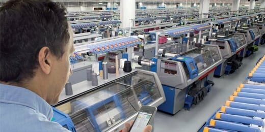 Bild eines Mitarbeiters in der Maschinenhalle der H. Stoll AG & Co. KG mit Handy in der Hand, valantic Case Study Stoll Strickmaschinen