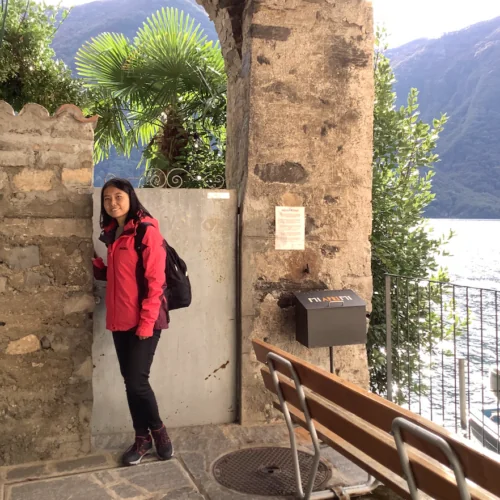 Picture of Cissy Hu, User Experience Specialist at valantic, in front of a stone wall with plants and water in the background