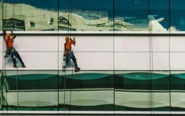 Bild von zwei Personen, die die Außenfassade eines Gebäudes reinigen, valantic Objektmanagement