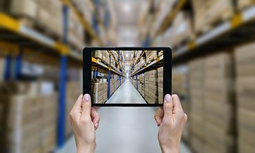 Picture of a tablet in a warehouse full of boxes, valantic logistics management
