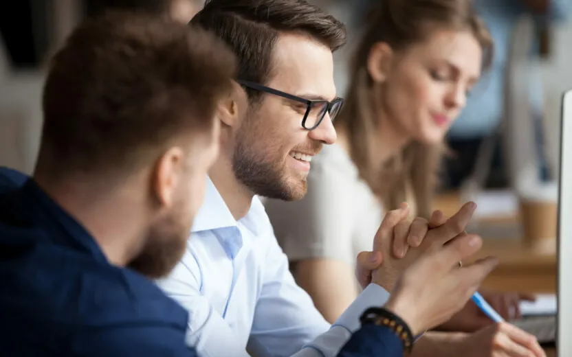 Close up of male colleagues cooperating in coworking office space talking laughing together