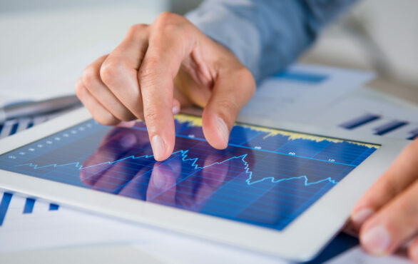 Closeup einer Hand, die auf einem Tablet zoomt, auf dem eine Grafik zu sehen ist, Finanzwesen