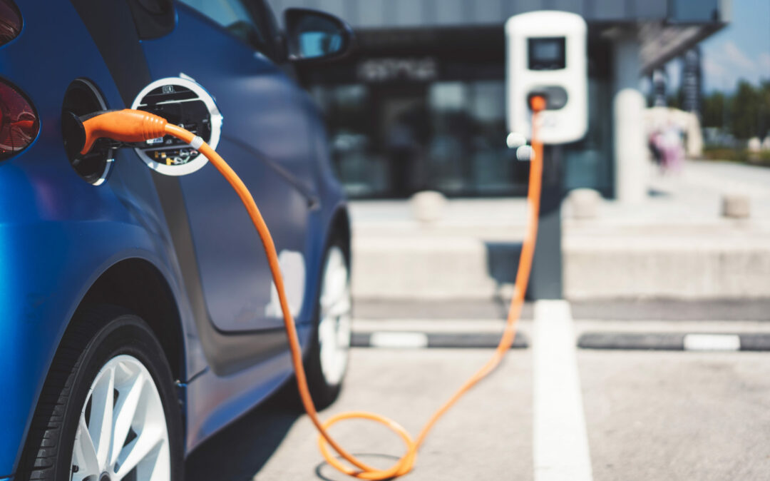 Image of an electric car charging at a charging station, trends in the automotive industry: Sustainability
