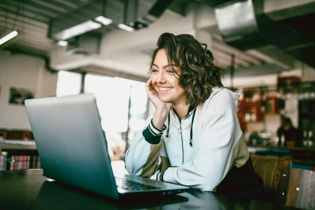 Image of a smiling woman looking into a laptop, trends in the automotive industry: Customer Experience