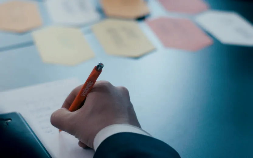Bild von mehreren farbigen Notizzetteln sowie einer Hand, die mit einem valantic Kugelschreiber etwas notiert
