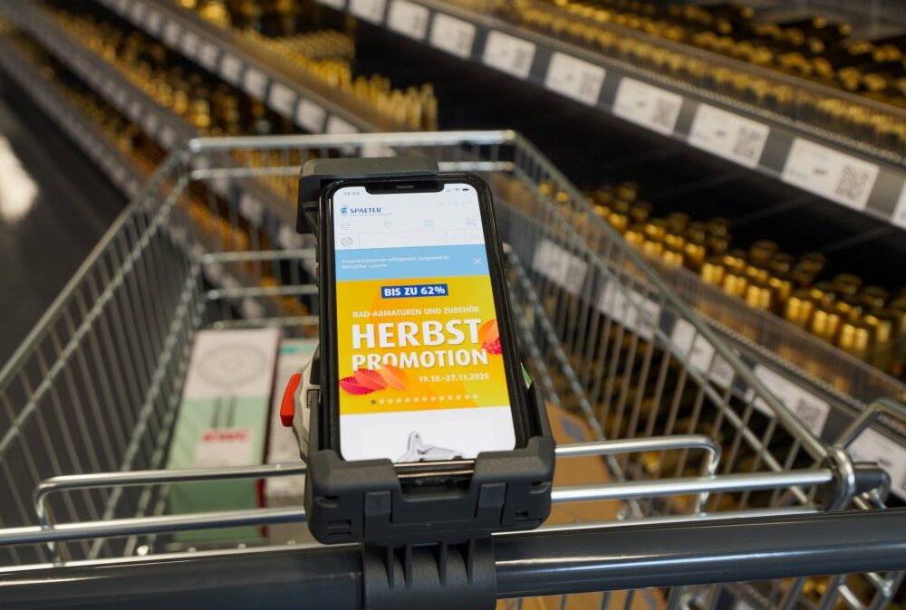Spaeter Store Smartphone am Einkaufswagen im Supermarkt