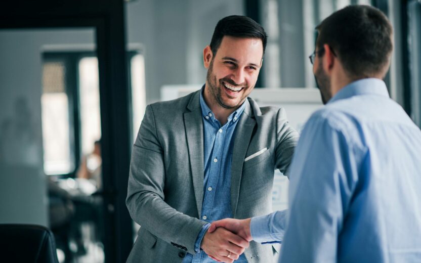 Two men smiling at each other during the handshake | Success Story SBB: Corporate Planning with Anaplan