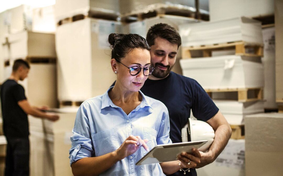 Bild von einer Frau, die in einem Lager steht und auf ein Tablet schaut, Supply Chain Management und Logistik, Leistungsangebot valantic