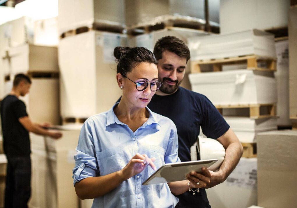 Bild von einer Frau, die in einem Lager steht und auf ein Tablet schaut, Supply Chain Management und Logistik, Leistungsangebot valantic