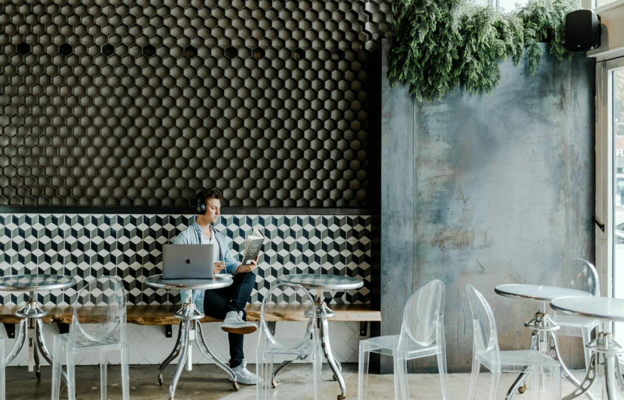 Bild von einem Mann im Café mit Laptop und Buch, Digital Now Magazin valantic New Work