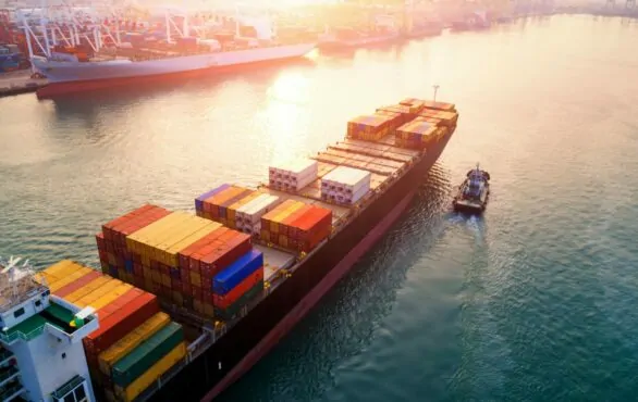 Bild eines Containerschiffes, das in einen Industriehafen einläuft; valantic Smart Industries & Industrie 4.0
