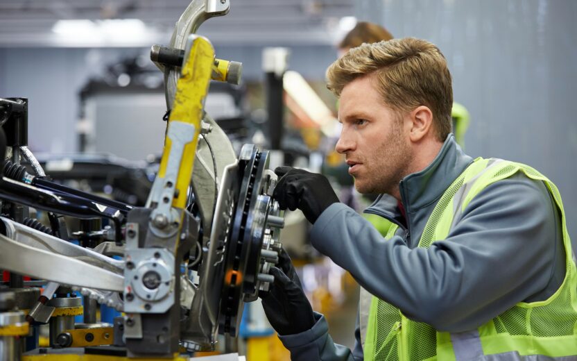 Männlicher Ingenieur, der das Fahrgestell eines Autos untersucht; valantic Smart Industries & Industrie 4.0