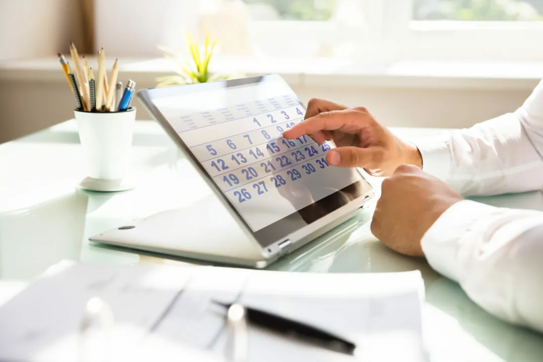 Close up of hand of businessman using calendar on laptop computer