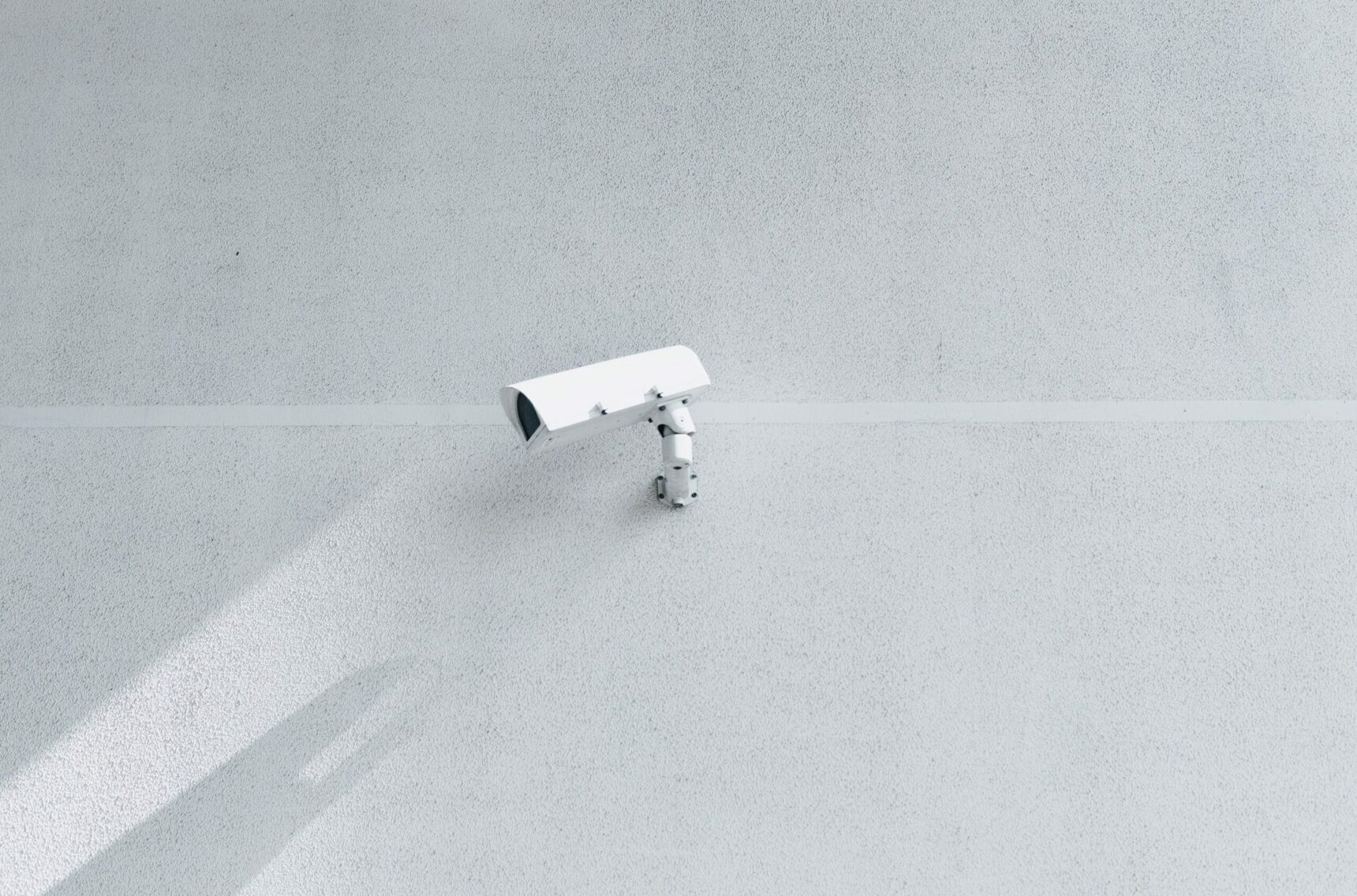 Bild von einer weißen Sicherheitskamera an einem Gebäude, Anbieter und Hersteller zu IT-Sicherheit verpflichten