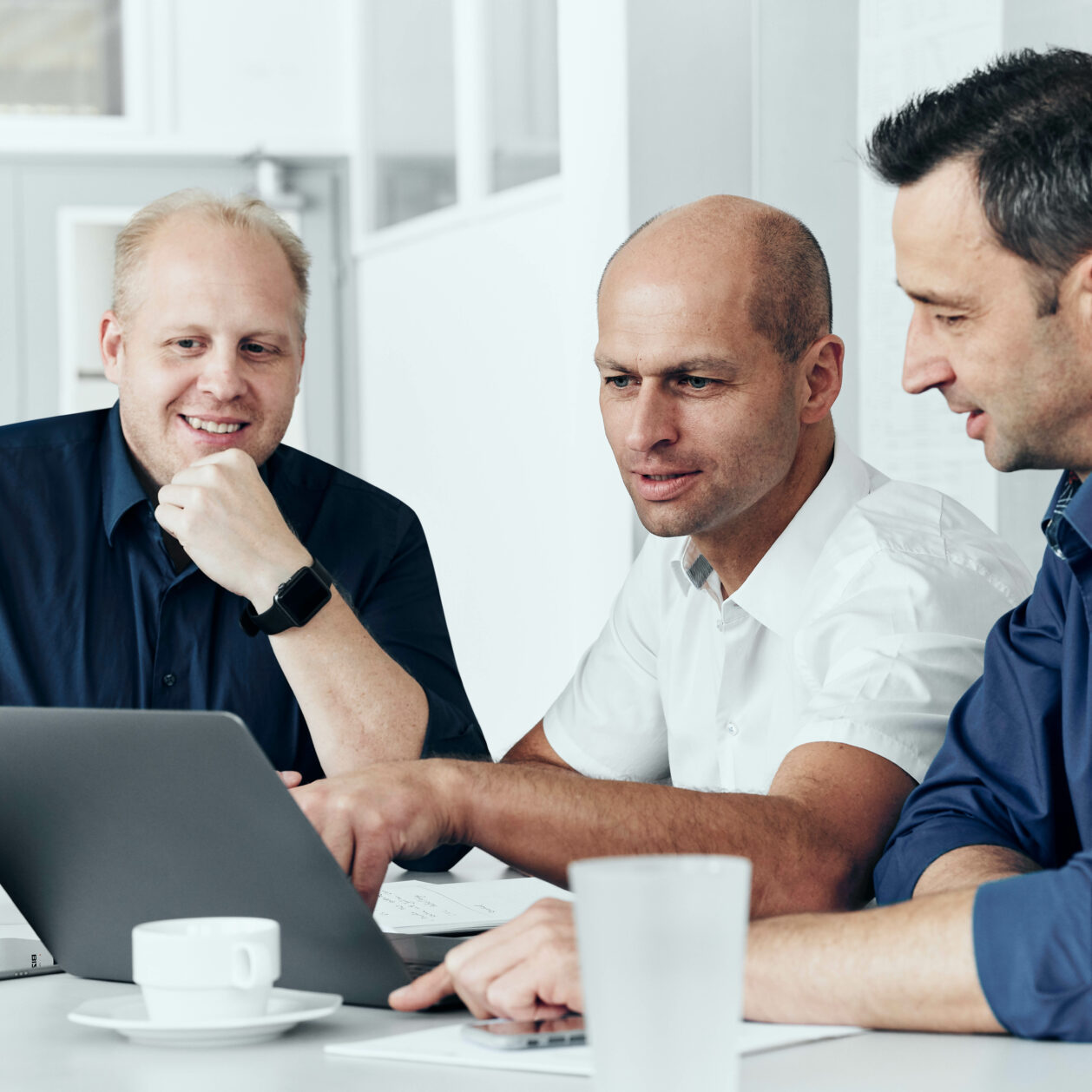 Photo of 3 Bizerba employees discussing a presentation on a laptop.