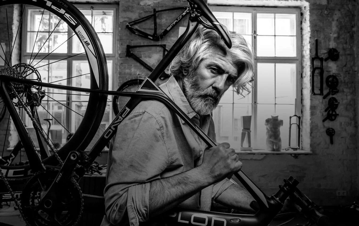 Bild von einem älteren Herrn in einer Fahrradwerkstatt, der ein SIMPON-Fahrrad schultert.