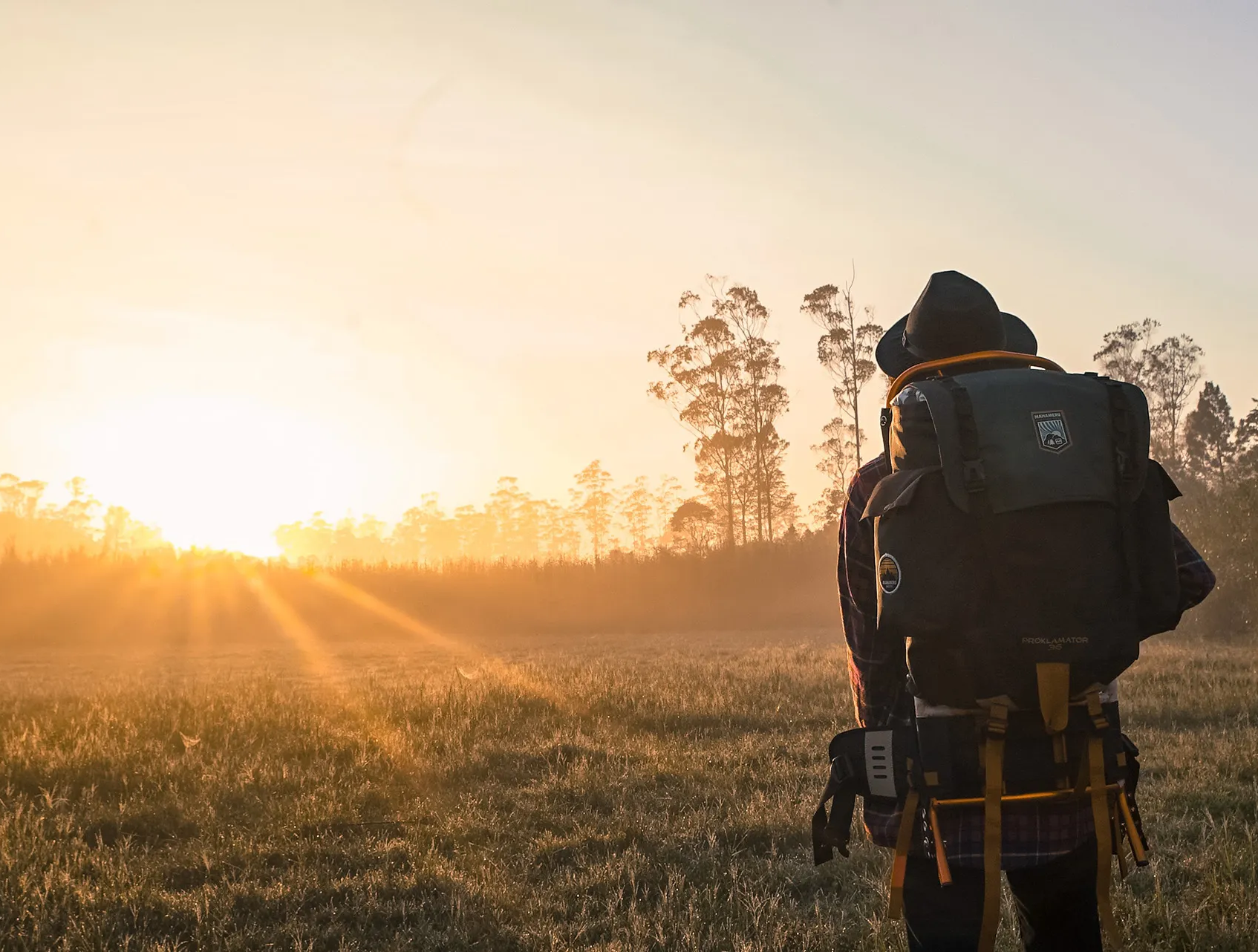 Man met backpack in de natuur met opkomende zon