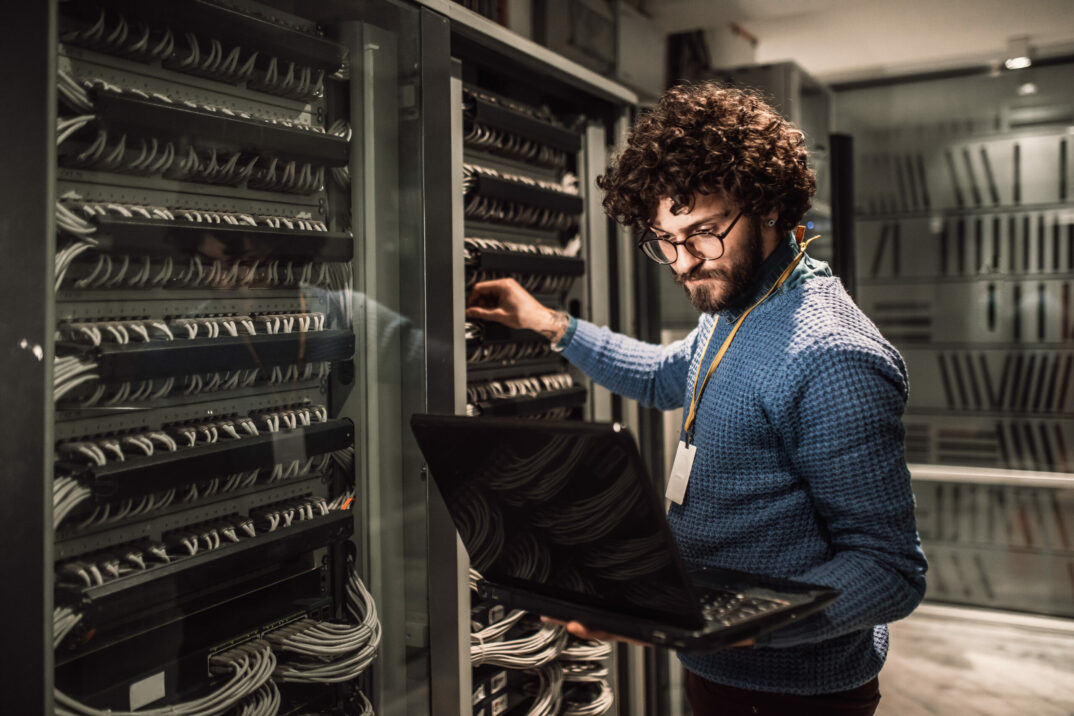 Bild von einem Mann mit Laptop in einem Serverraum | INTARGIA Success Story Cyberangriff