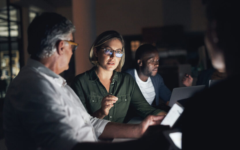 Image of a group of colleagues having a meeting in an office late at night, Success Story Cyberattack