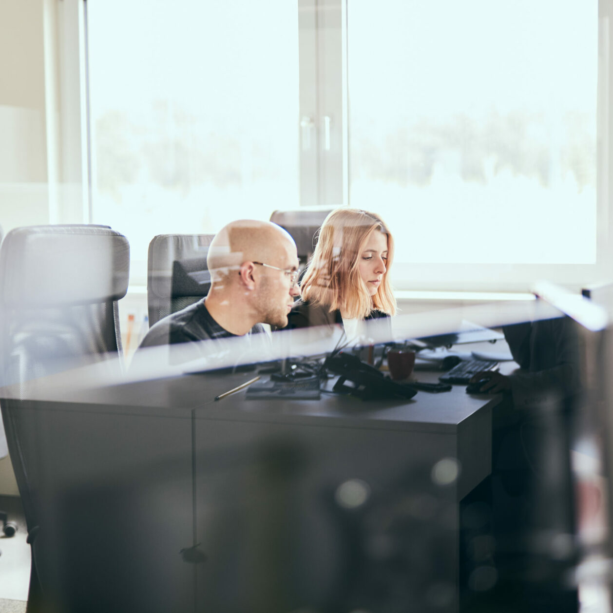 Foto von einem Mann und einer Frau, die an einem Büroarbeitsplatz sitzen und miteinander reden.