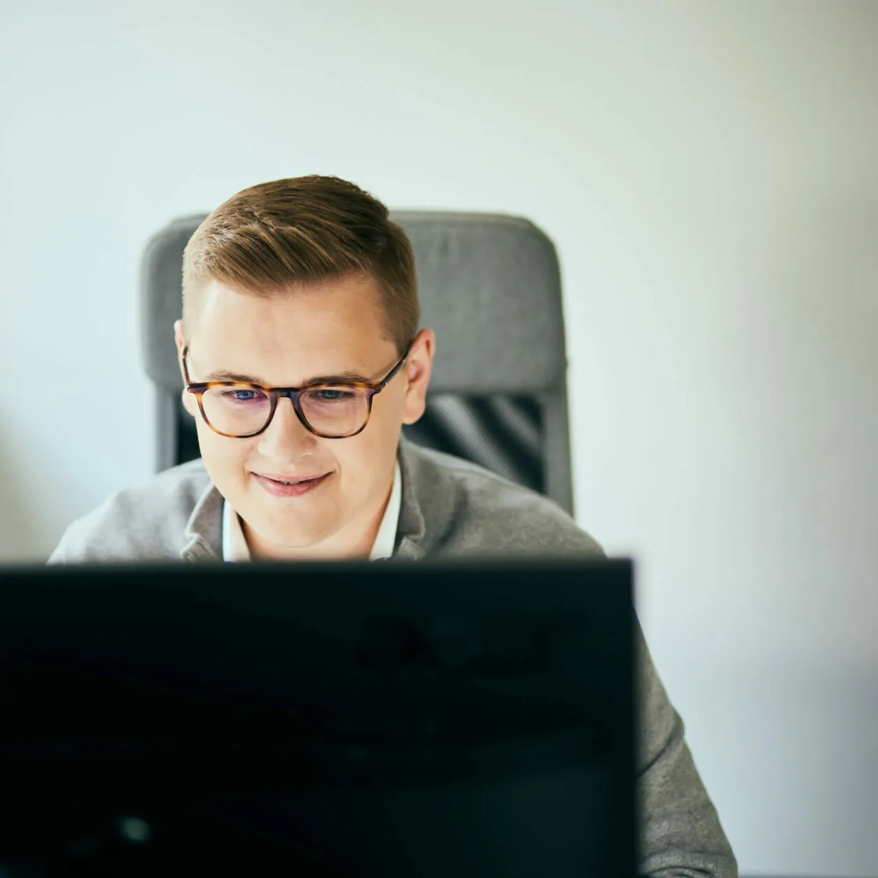 Foto von einem Mann mit Brille, der in einen Computerbildschirm schaut.